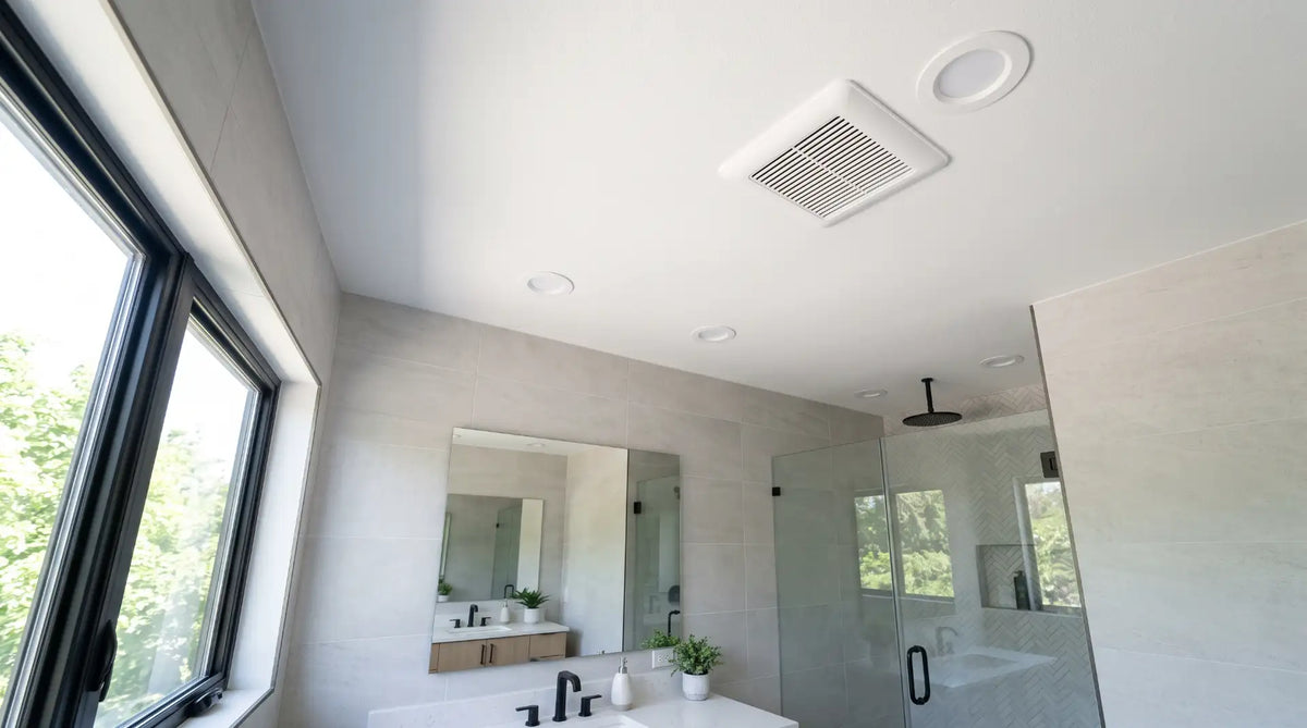 A modern ceiling-mounted bathroom exhaust fan installed in a clean white ceiling with contemporary tile finishing.