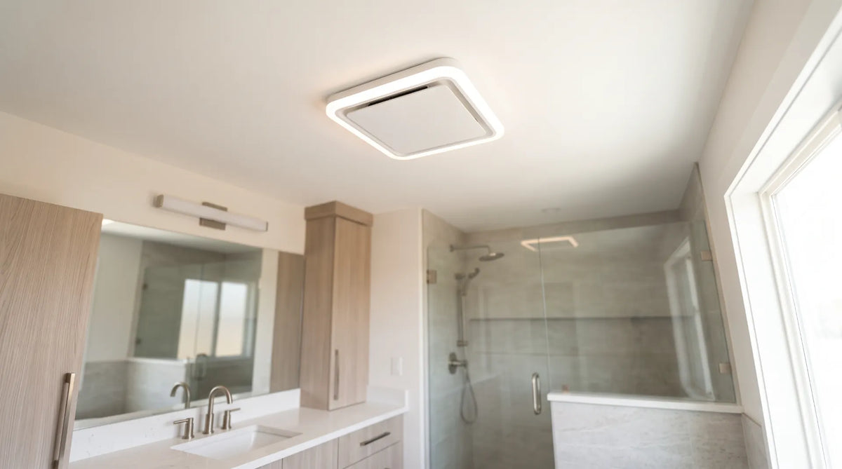 Modern luxury primary bathroom ceiling featuring a sleek, low-profile white exhaust fan with integrated LED lighting next to a modern glass shower.